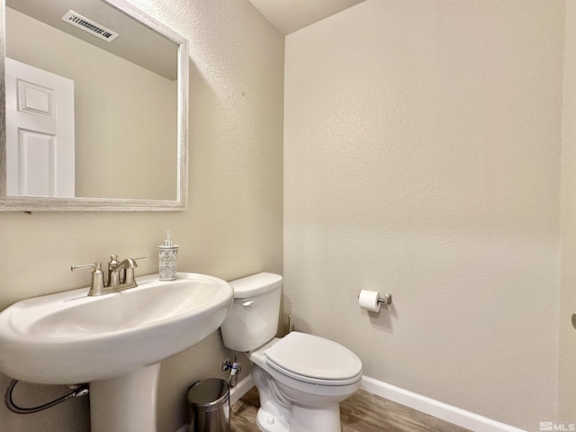 bathroom featuring wood-type flooring, sink, and toilet