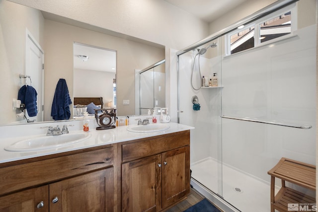 bathroom with a shower with door, vanity, and a healthy amount of sunlight