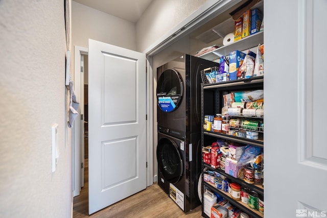 clothes washing area with stacked washer and clothes dryer and light hardwood / wood-style floors