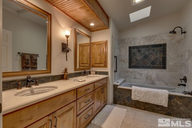 bathroom featuring vanity, vaulted ceiling with skylight, and tiled shower / bath combo