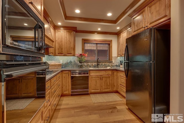 kitchen with sink, light hardwood / wood-style flooring, ornamental molding, decorative backsplash, and black appliances