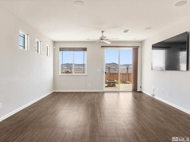 spare room with dark hardwood / wood-style flooring, ceiling fan, and a healthy amount of sunlight