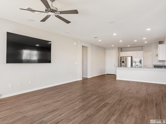 unfurnished living room with dark hardwood / wood-style floors and ceiling fan