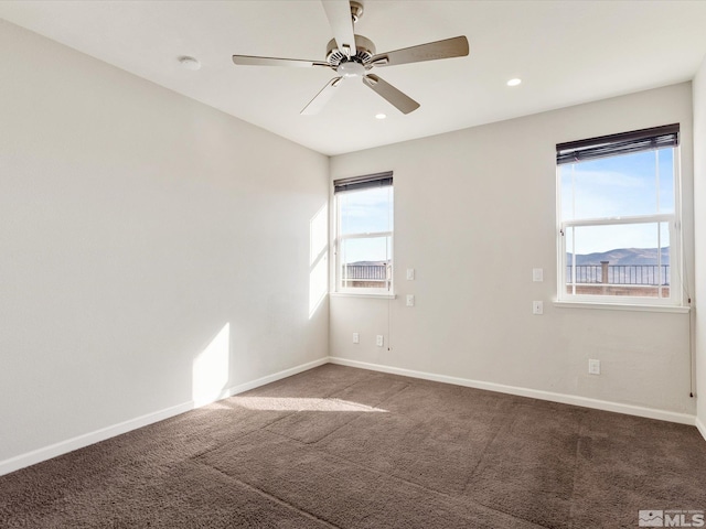 empty room featuring ceiling fan, a mountain view, and carpet