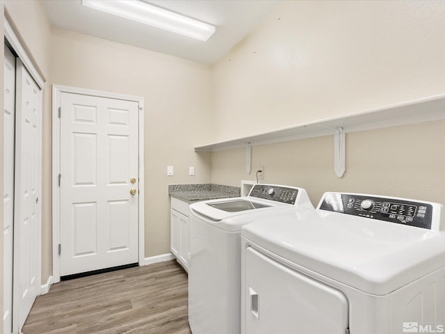 laundry area with cabinets, washer and dryer, and light hardwood / wood-style flooring