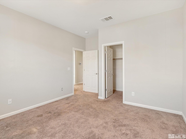 unfurnished bedroom featuring a spacious closet, light colored carpet, and a closet