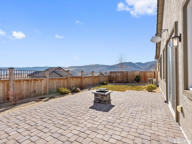 view of patio with cooling unit, a mountain view, and an outdoor fire pit