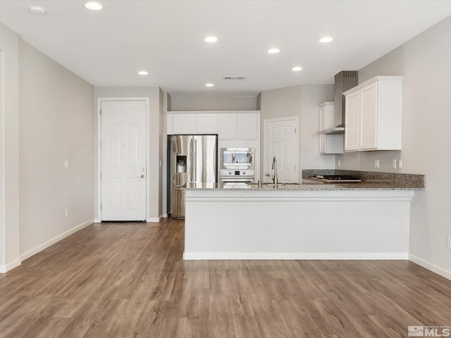 kitchen with appliances with stainless steel finishes, white cabinetry, sink, kitchen peninsula, and wall chimney range hood