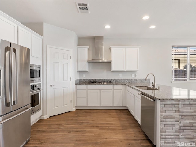 kitchen with white cabinetry, appliances with stainless steel finishes, sink, and wall chimney exhaust hood