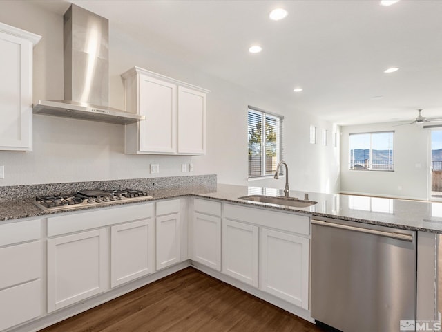 kitchen featuring sink, white cabinetry, stainless steel appliances, stone countertops, and wall chimney exhaust hood