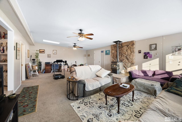 carpeted living room with ceiling fan and a wood stove