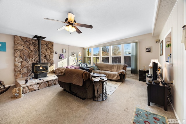 carpeted living room with a wood stove and ceiling fan