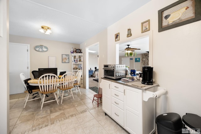 kitchen with a textured ceiling, white cabinets, ceiling fan, and light tile patterned floors