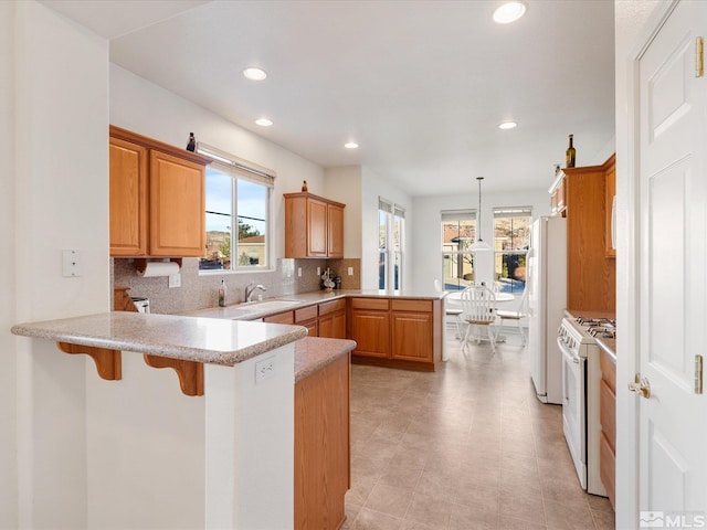 kitchen featuring tasteful backsplash, hanging light fixtures, a kitchen breakfast bar, kitchen peninsula, and white appliances