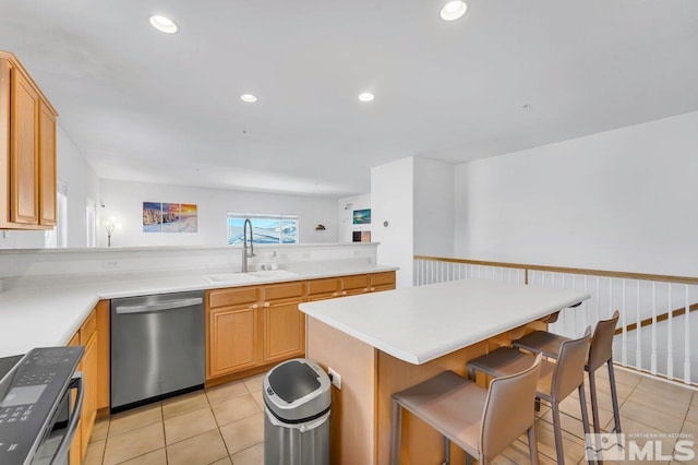 kitchen featuring light tile patterned flooring, a breakfast bar, sink, appliances with stainless steel finishes, and a kitchen island