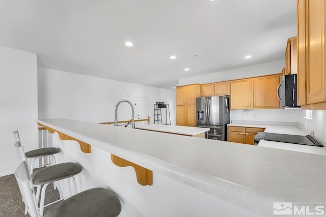 kitchen featuring appliances with stainless steel finishes, a breakfast bar, carpet, and kitchen peninsula