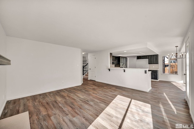 unfurnished living room with dark wood-type flooring and a notable chandelier