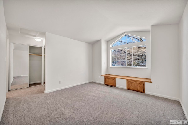 unfurnished bedroom featuring vaulted ceiling, light colored carpet, and a closet