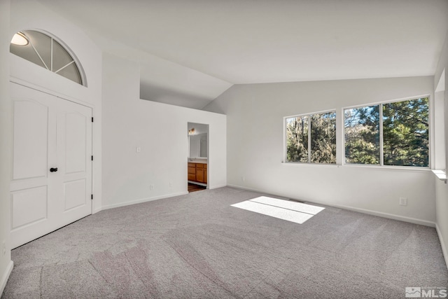 interior space with a closet, lofted ceiling, connected bathroom, and carpet