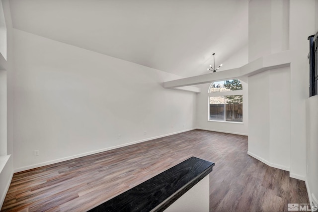 interior space with wood-type flooring, high vaulted ceiling, and an inviting chandelier