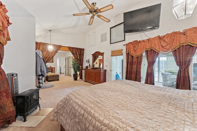 carpeted bedroom featuring vaulted ceiling, ceiling fan, and a wood stove