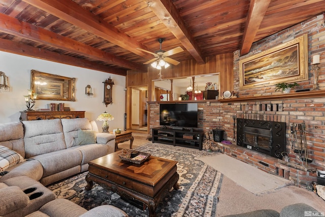 living room featuring beamed ceiling, ceiling fan, a fireplace, and wood walls