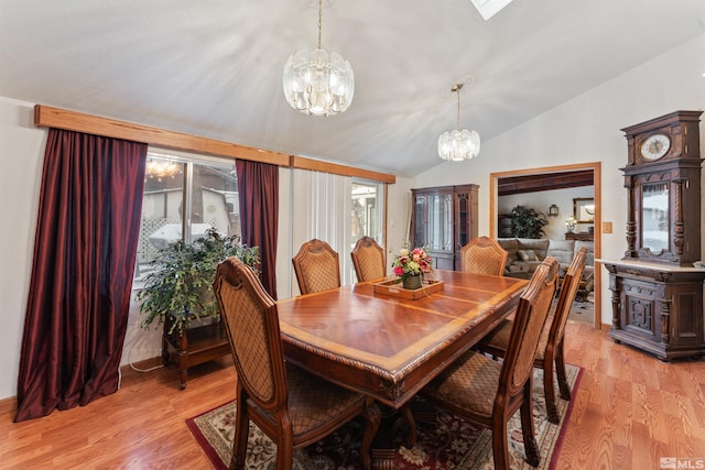 dining space featuring a notable chandelier, vaulted ceiling, and light hardwood / wood-style floors