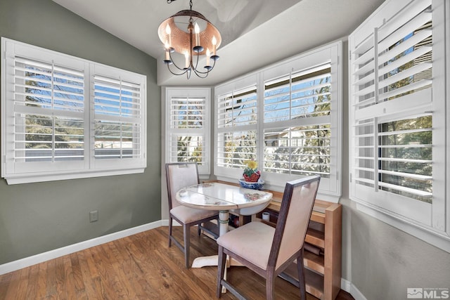 dining space with hardwood / wood-style flooring, vaulted ceiling, and a chandelier