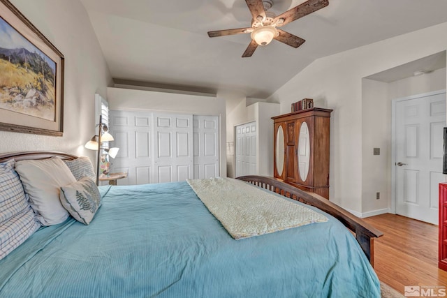 bedroom with ceiling fan, two closets, vaulted ceiling, and light wood-type flooring