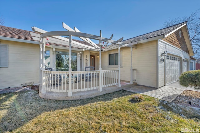 back of property featuring a garage, covered porch, and a lawn