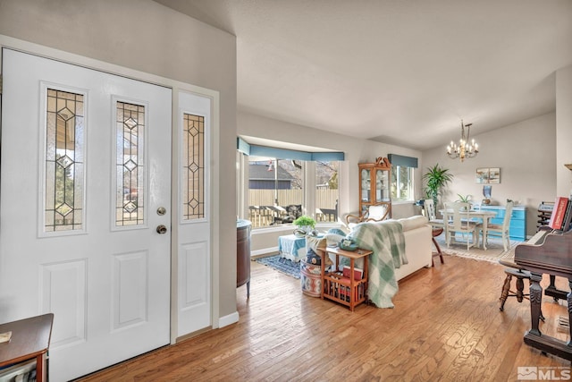 entrance foyer with an inviting chandelier, vaulted ceiling, and light hardwood / wood-style floors