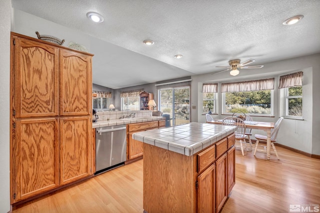 kitchen featuring light hardwood / wood-style flooring, tile countertops, a center island, and dishwasher