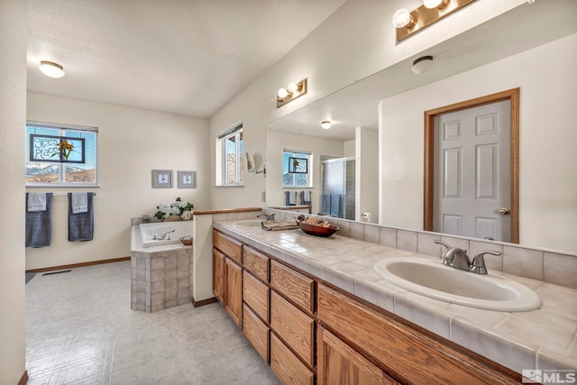 bathroom featuring a healthy amount of sunlight, independent shower and bath, and vanity