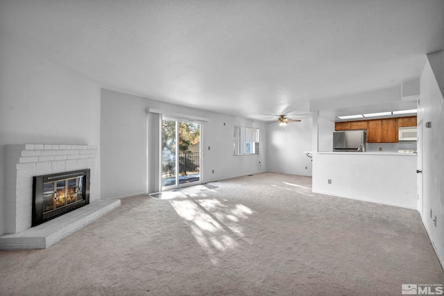 unfurnished living room with a brick fireplace, light carpet, and ceiling fan