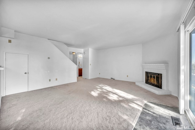 unfurnished living room with a brick fireplace and carpet