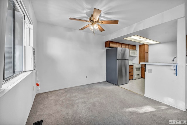 kitchen featuring ceiling fan, white appliances, kitchen peninsula, and light carpet