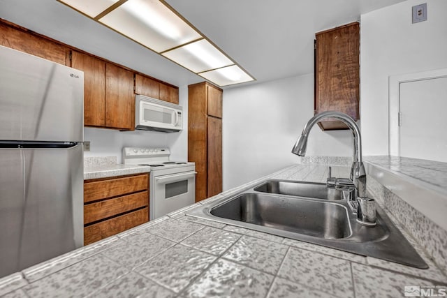 kitchen with sink, white appliances, and tile countertops