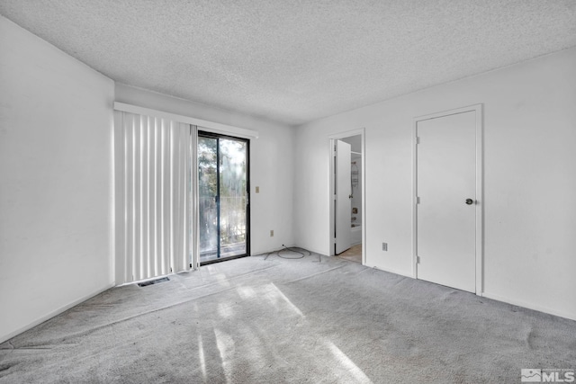 carpeted empty room featuring a textured ceiling