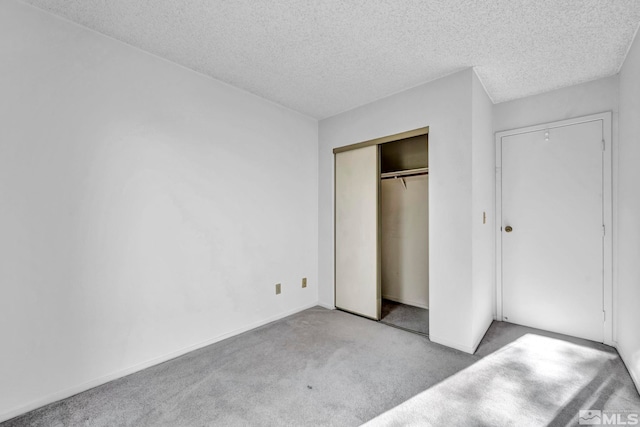 unfurnished bedroom featuring light carpet, a textured ceiling, and a closet