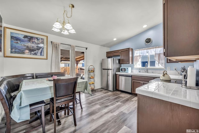 kitchen featuring a healthy amount of sunlight, appliances with stainless steel finishes, tile countertops, and decorative light fixtures