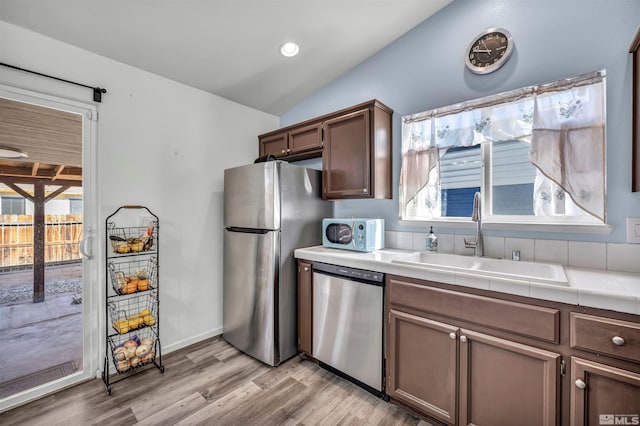 kitchen with vaulted ceiling, appliances with stainless steel finishes, sink, and a wealth of natural light