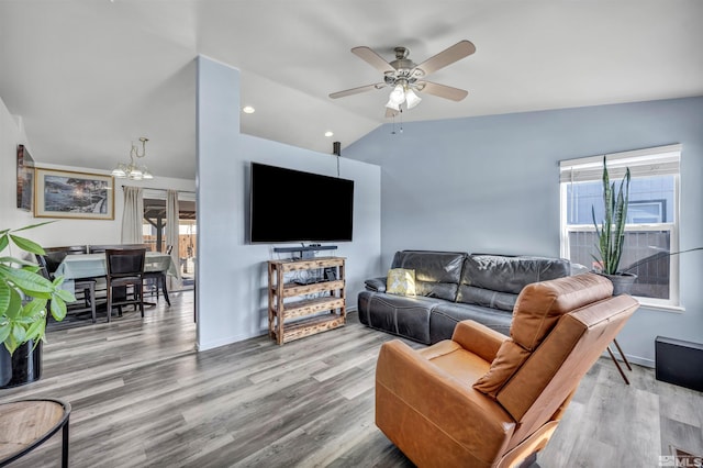 living room featuring hardwood / wood-style flooring, vaulted ceiling, and ceiling fan with notable chandelier