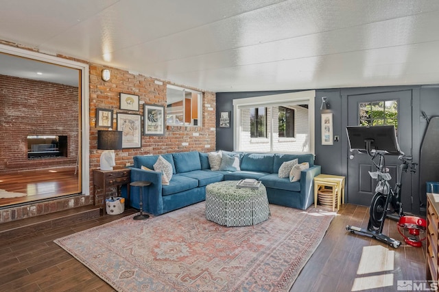 living room with brick wall and dark hardwood / wood-style flooring