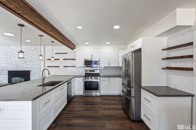 kitchen featuring appliances with stainless steel finishes, white cabinetry, sink, hanging light fixtures, and kitchen peninsula