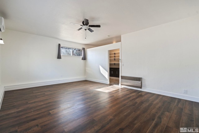 unfurnished room with heating unit, dark hardwood / wood-style flooring, a wall mounted AC, and ceiling fan