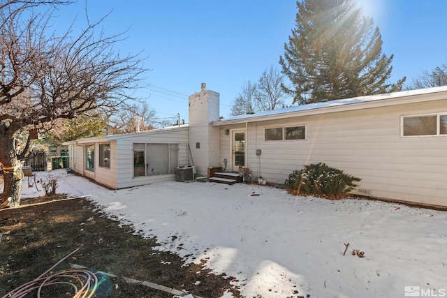 snow covered back of property featuring central AC