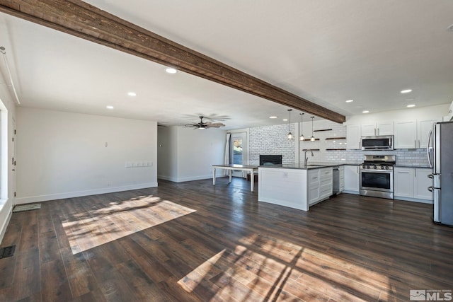 kitchen with sink, appliances with stainless steel finishes, hanging light fixtures, beam ceiling, and white cabinets