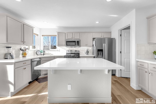 kitchen featuring sink, a breakfast bar area, stainless steel appliances, a center island, and light wood-type flooring