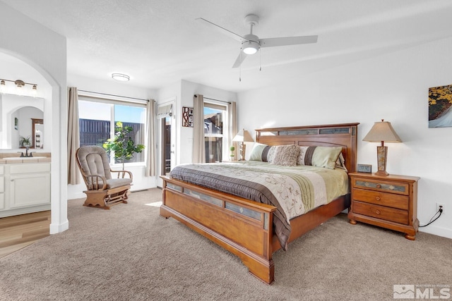 bedroom featuring sink, ceiling fan, access to exterior, ensuite bathroom, and light carpet