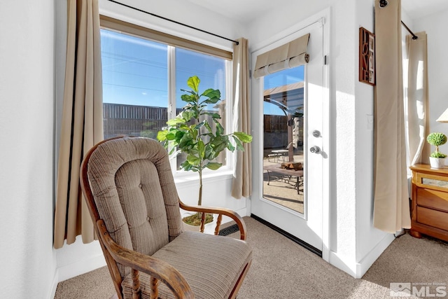 doorway to outside featuring light carpet and a wealth of natural light